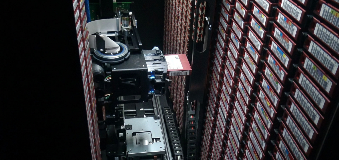 A robotic tape library selecting one barcode-indexed record from a dense archival store.